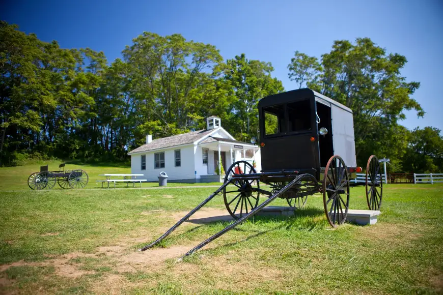Traditional Amish buggy parked outside a one-room schoolhouse at The Amish Village in Lancaster PA