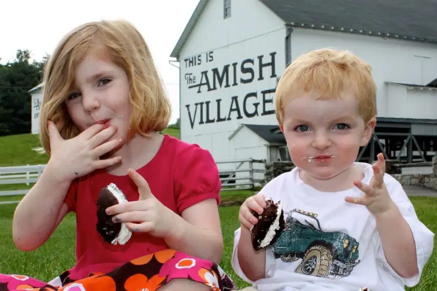 Kids eating whoopie pies in front of The Amish Village barn in Lancaster PA, Amish country food and family fun