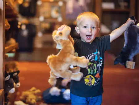 Excited child playing with animal stuffed toys in the gift shop at Sight and Sound Theatres in Lancaster PA