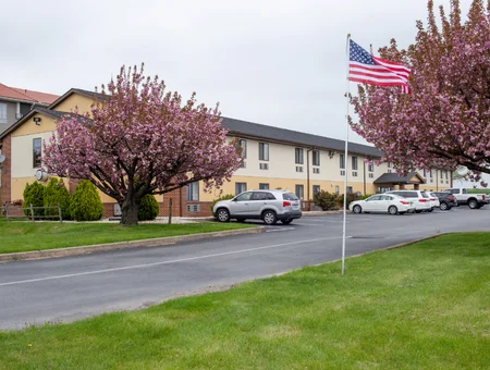 Exterior of Eastbrook Inn with flowering trees, an American flag, and parking lot