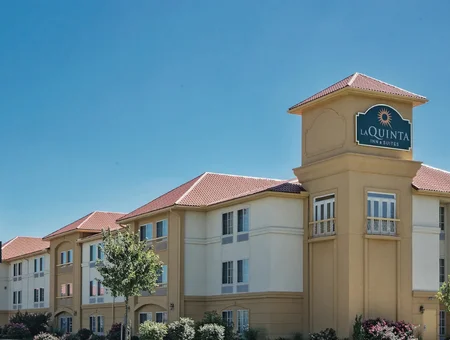 Exterior of La Quinta Inn and Suites with a tower entrance and landscaped grounds