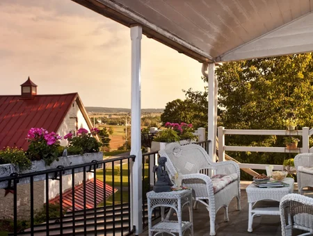 Wicker furniture on a covered porch overlooking farmland at sunset, Artist's Inn and Gallery