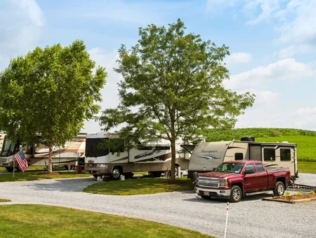 RVs and a truck parked at a wooded campsite at Country Acres Campground