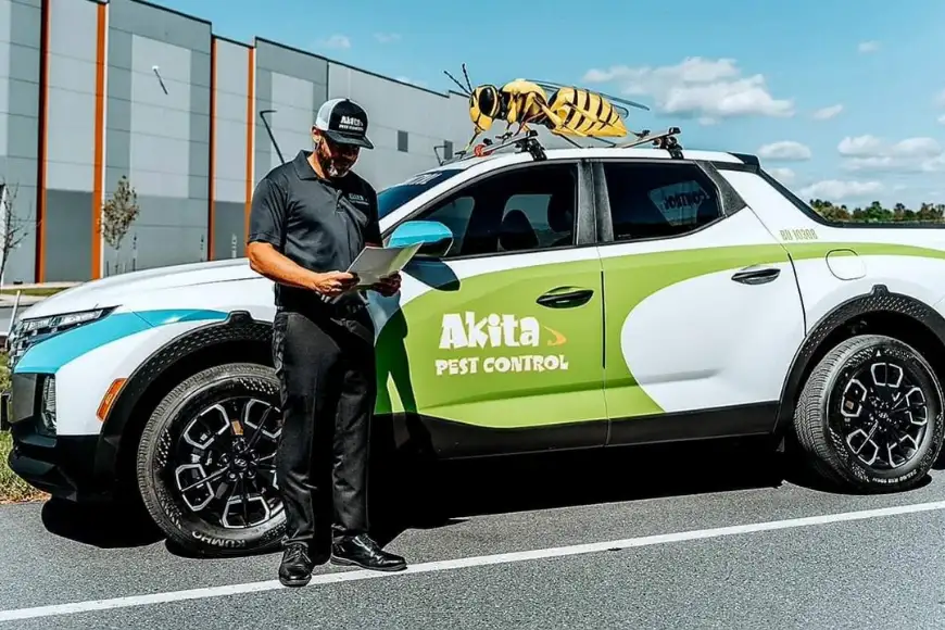 Akita Pest Control technician reviewing service notes next to branded vehicle with giant wasp on roof in Lancaster PA