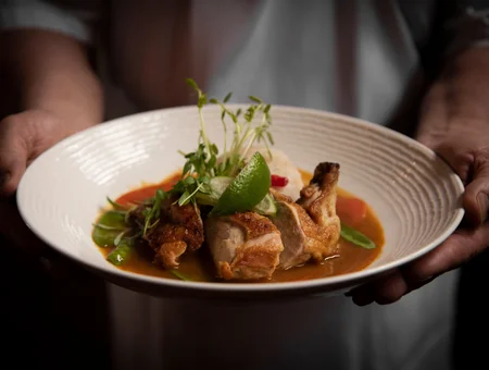 Chef presenting braised chicken with herb broth and microgreens at The Log Cabin Restaurant Lancaster PA