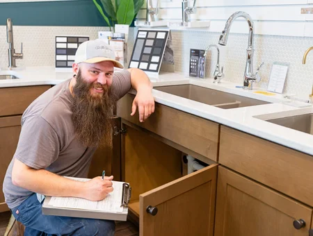 Mervin Zimmerman plumber inspecting under kitchen sink cabinet with clipboard in Lancaster PA