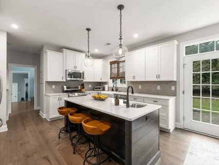 Custom white kitchen with gray island, quartz countertops, and globe pendant lights by Kauffman Kitchens in Lancaster PA