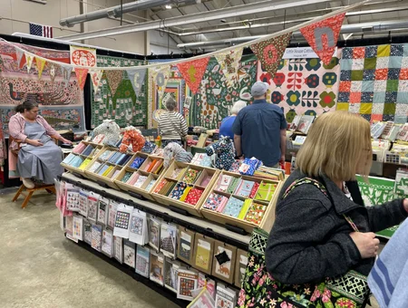 Vendor booth with hanging quilts and fabric squares for sale at Lancaster Quilt Show