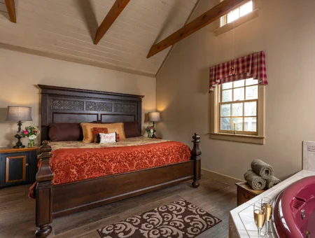 Bedroom with a carved wood bed frame, whirlpool tub, and champagne glasses at Inn and Spa at Leola Village