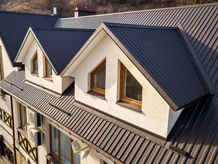 Standing seam metal roof with wood frame dormer windows on stucco home by J&E Contracting in Lancaster PA
