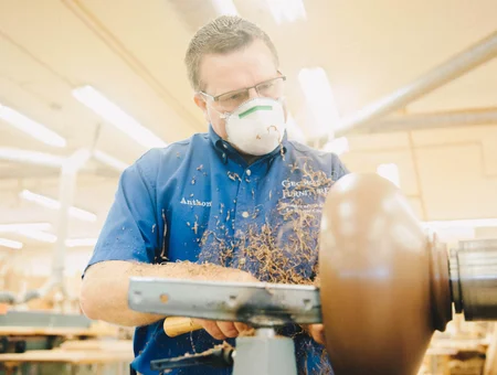 Craftsman turning wood on a lathe at George's Furniture factory in Lancaster PA