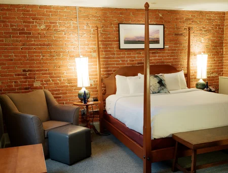 Four-poster bed against an exposed brick wall in a suite at Lancaster Arts Hotel