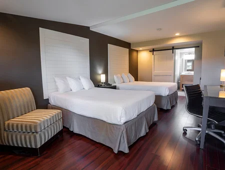 Modern hotel room with two beds, a sliding barn door, and a small desk at Hershey Farm Resort