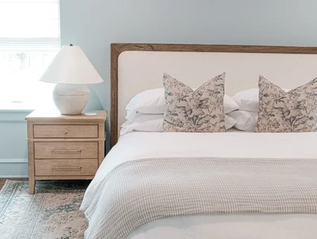 Upholstered bed with floral pillows and a wood nightstand at Mill Creek Manor
