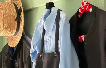 Traditional Amish clothing and straw hat hanging on hooks, Amish farm tour in Lancaster PA
