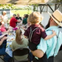 Tourists sharing an outdoor meal with an Amish host family at The Amish Farm and House in Lancaster County PA