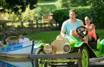 Family riding vintage car ride at Dutch Wonderland amusement park in Lancaster PA