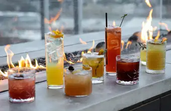 The Exchange Lancaster craft cocktails lineup with fire pit backdrop - rooftop bar Lancaster PA