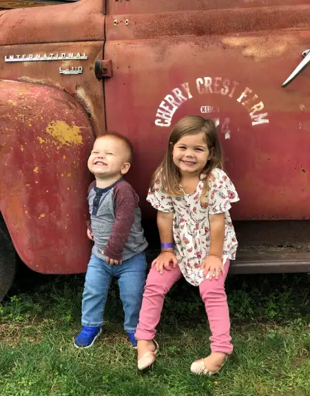 Two young kids posing in front of a vintage Cherry Crest Farm truck in Ronks Lancaster County PA