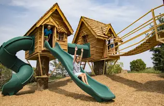 Kids playing on wooden treehouse playground structure at a Lancaster PA amusement park