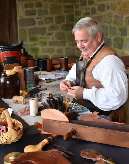 Colonial craftsman demonstrating traditional leatherworking on a field trip at Landis Valley Village and Farm Museum in Lancaster PA
