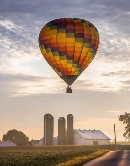 Hot air balloon floating over Amish farm silos at sunset in Lancaster County PA