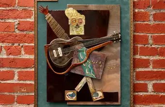 Mixed media artwork with guitar displayed on brick wall at a Lancaster PA art gallery