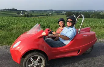 Couple riding a red scooter car through Lancaster County PA farmland