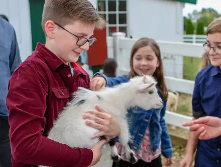 Amish Farm and House petting zoo with kids holding baby goat during family Amish tour in Lancaster PA