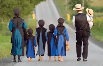 Amish father and children walking along a rural road in Lancaster County PA