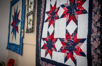 Red white and blue star pattern Amish handmade quilts displayed at Lancaster County PA quilt shop