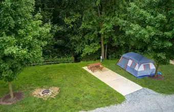 Aerial view of a tent campsite with fire pit surrounded by trees at Jellystone Park campground in Lancaster PA