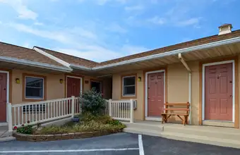 Exterior of Red Carpet Inn motel with covered porch and parking, affordable hotel in Lancaster PA