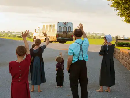 Amish family waving to countryside tour bus during guided Amish Farm and House tour in Lancaster County PA