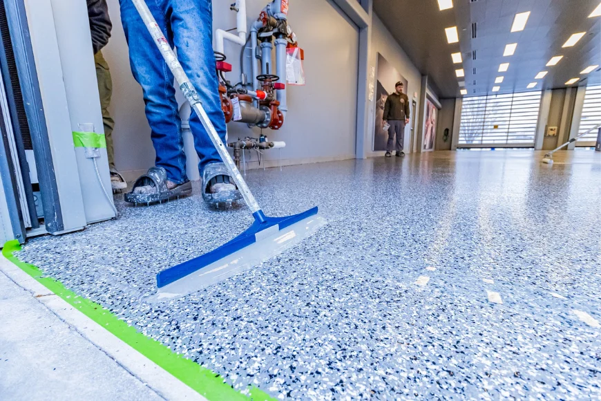 Contractor applying flake epoxy floor coating with squeegee in commercial building by Epoxy Floor Experts in Lancaster PA