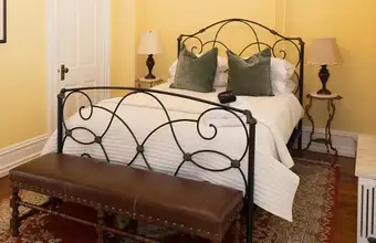 Iron scroll bed frame with leather bench in a cozy room at Freedom Home extended stay lodging in Lancaster PA