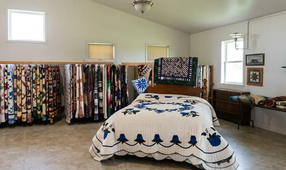 Handmade Amish quilts displayed on bed and rack at Smucker's Quilts in Lancaster County PA