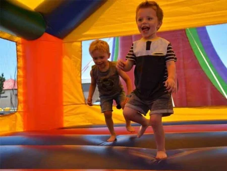 Two boys laughing and running inside a colorful bounce house rented from 3 Monkeys Inflatables