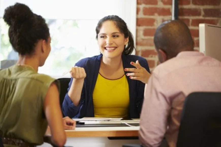 Advisor consulting with two clients at a desk in a brick office setting, used in a Bagnall Shaw Insurance ad