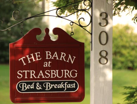 The Barn at Strasburg sign image: red hanging sign reading "The Barn at Strasburg Bed & Breakfast" mounted on the porch post at 308, in Lancaster, PA