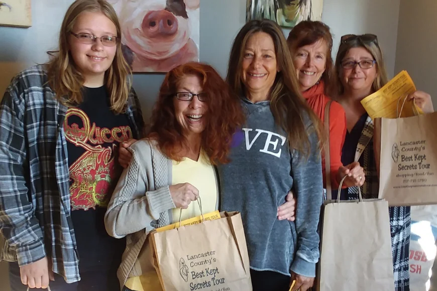 Group posing with shopping bags at an art gallery stop on the Best Kept Secrets Tour in Lancaster PA