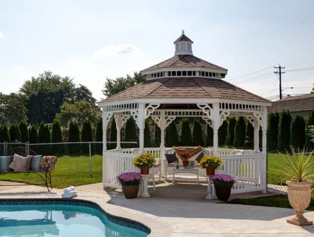 White Victorian gazebo with hammock and flowers beside backyard pool at Country Lane Gazebos Lancaster PA