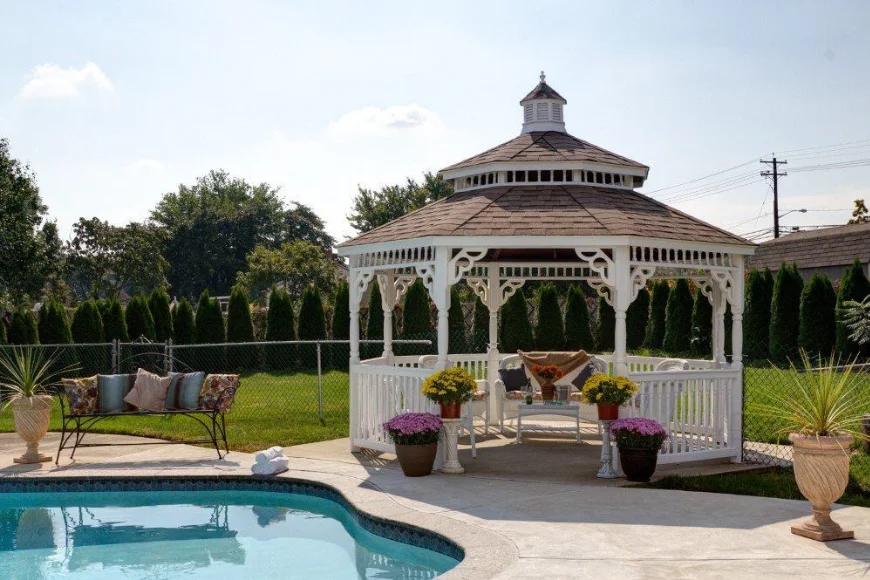 Large white Victorian gazebo with poolside seating and flower planters at Country Lane Gazebos Lancaster PA