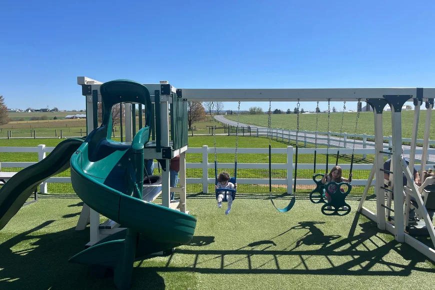Children playing on playground swings and slide at Countryside Road Stand Amish farm market in Lancaster PA