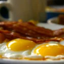 Sunny-side-up eggs with bacon and home fries at a diner near Dutch Wonderland, served with coffee in the background
