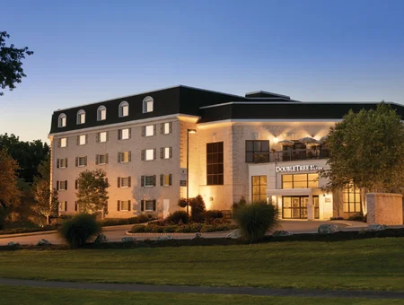DoubleTree Resort by Hilton Lancaster exterior at dusk, with illuminated windows, a landscaped entrance, and a rooftop patio area lit above the main entrance