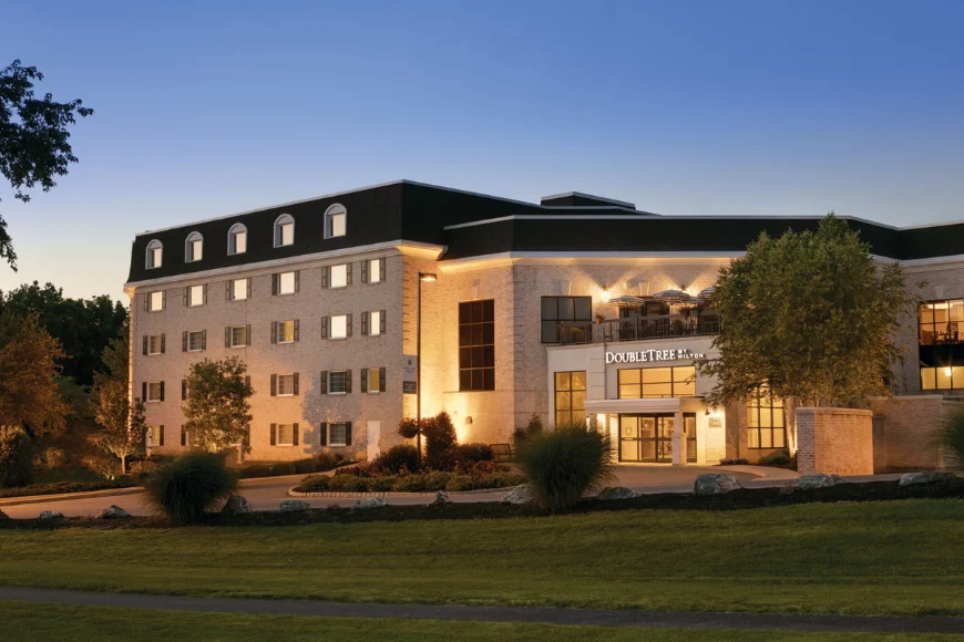 DoubleTree by Hilton Lancaster exterior at dusk, with warm lighting on the brick facade, a covered rooftop patio, and landscaped grounds in front