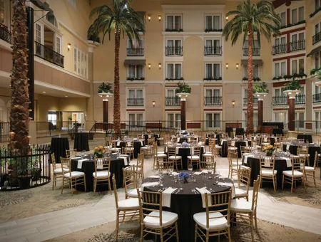 Round banquet tables set for an event in the atrium at DoubleTree Resort by Hilton Lancaster, surrounded by palm trees and balcony-style guest room floors