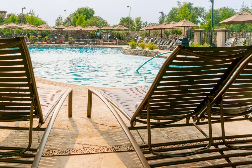 Lounge chairs beside an outdoor pool with umbrellas at Eden Resort and Suites