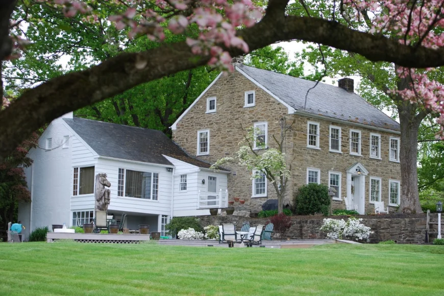 Historic stone farmhouse with patio and stone wall in spring at Shallowbrook Farm in Lancaster PA